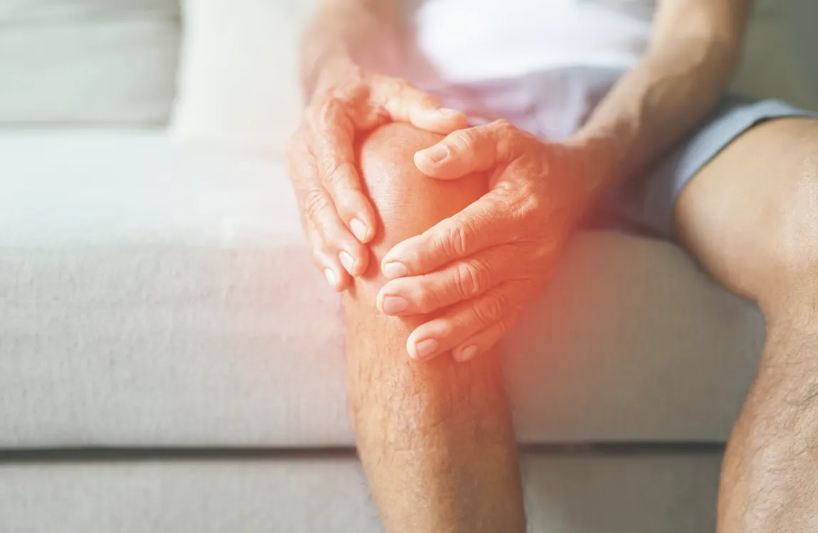 Elderly person holding their knee in pain