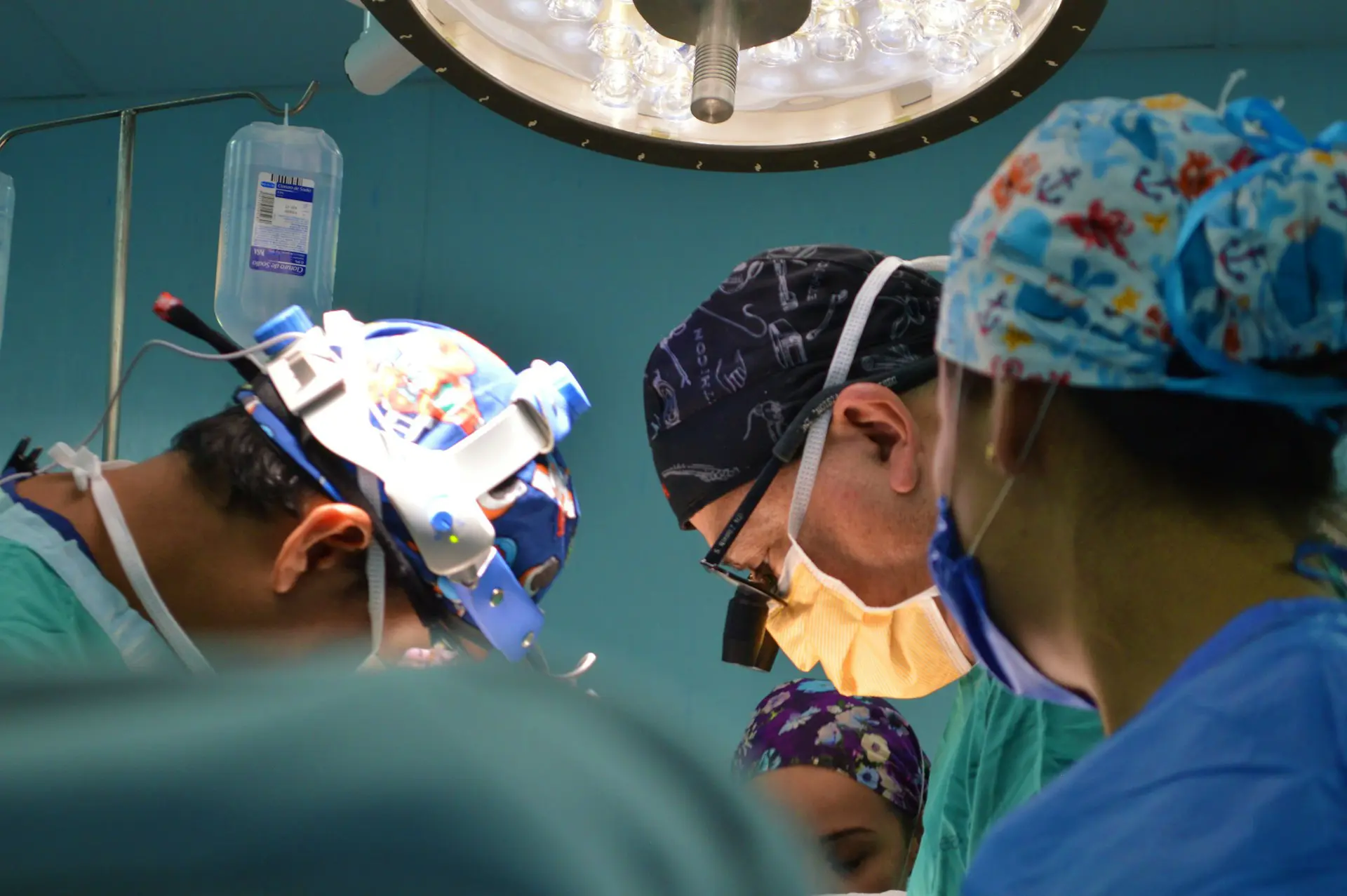 Three doctors in surgical attire working together during a medical procedure in an operating room